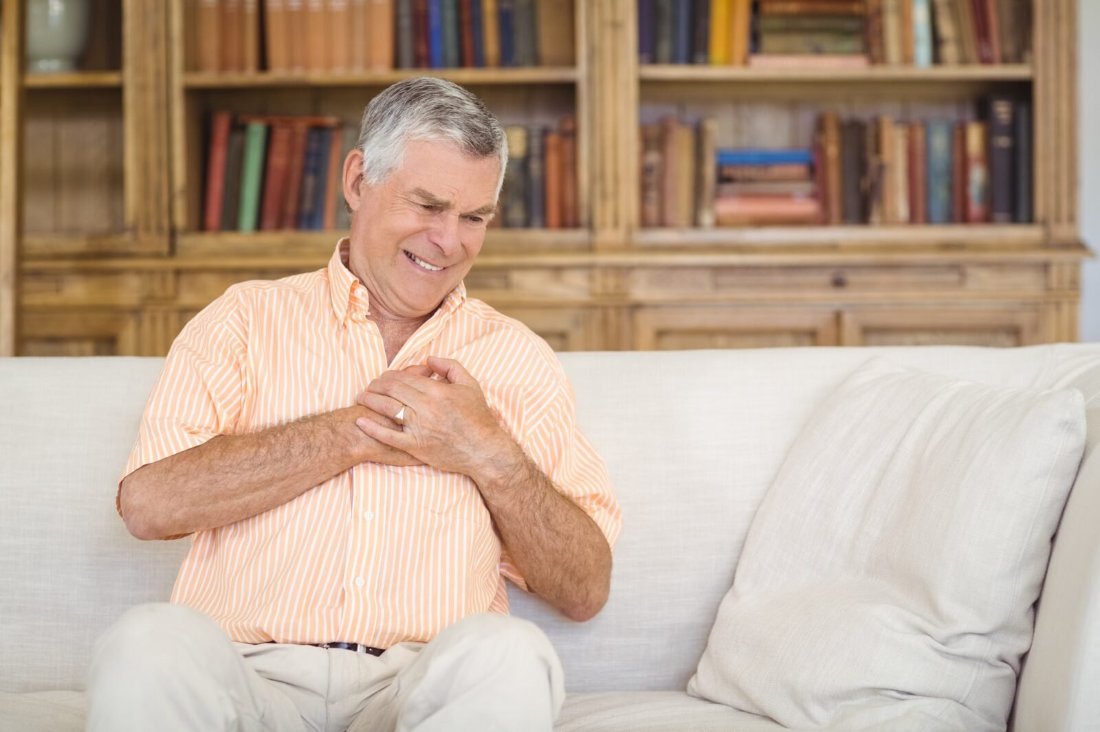 Senior man suffering from chest pain in living room