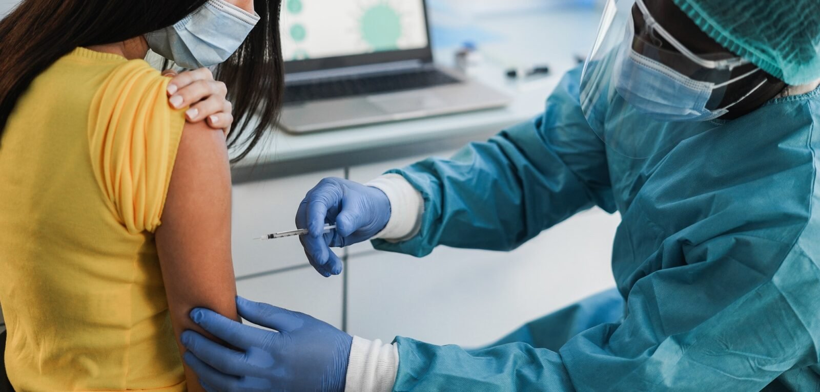 Doctor making an covid 19 vaccine injection to female patient - Focus on doctor right hand